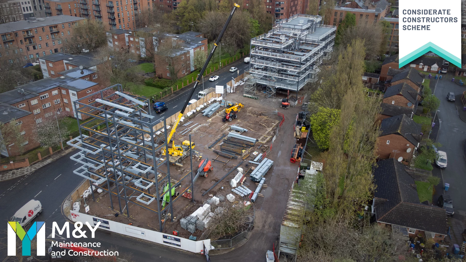 A birds eye view of Grove Street development in Liverpool, showing a site in mid development with steel frames raising three stores. M&Y Maintenance and Construction logo to the bottom left and the Considerate Construction Scheme logo to the top right.