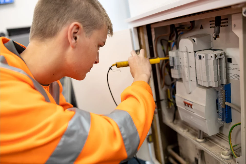 A technician in safety equipment assessing an electrical switch board